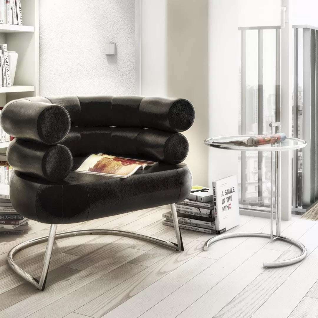 Modern black leather chair in a minimalistic living room with books and a magazine.