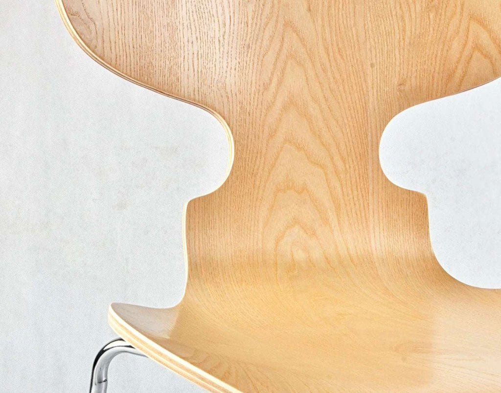 Close-up of a wooden chair with a white cushion on a light gray background