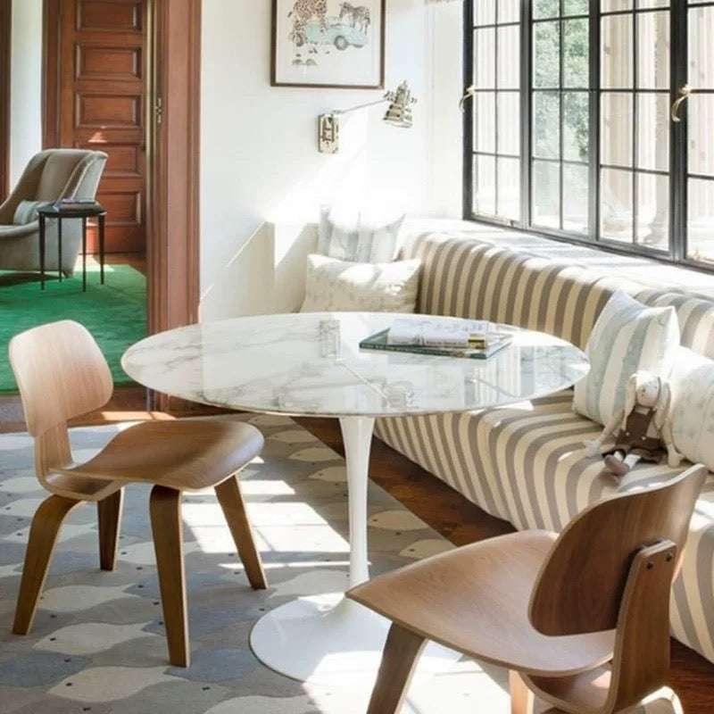 Modern dining area with marble table, wooden chairs, and striped sofa.
