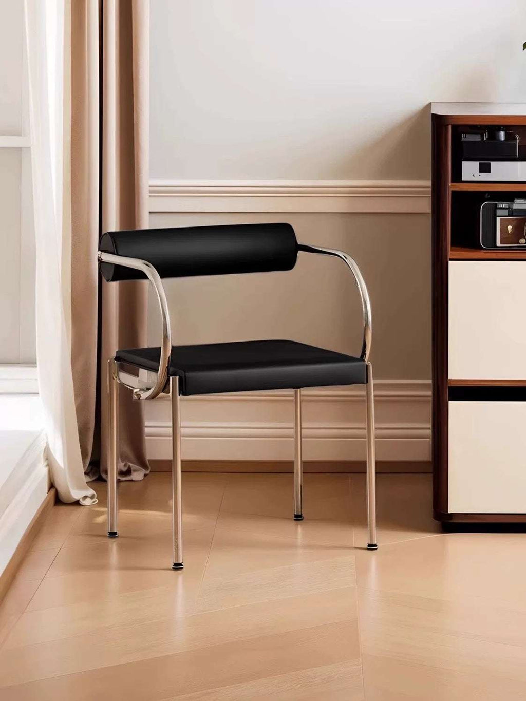 Modern black chair with chrome legs in a room with a bookshelf.