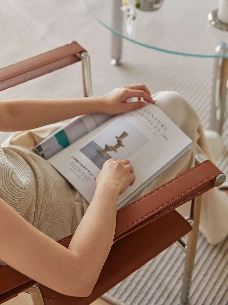 Person sitting on a chair holding an open book in a modern interior setting