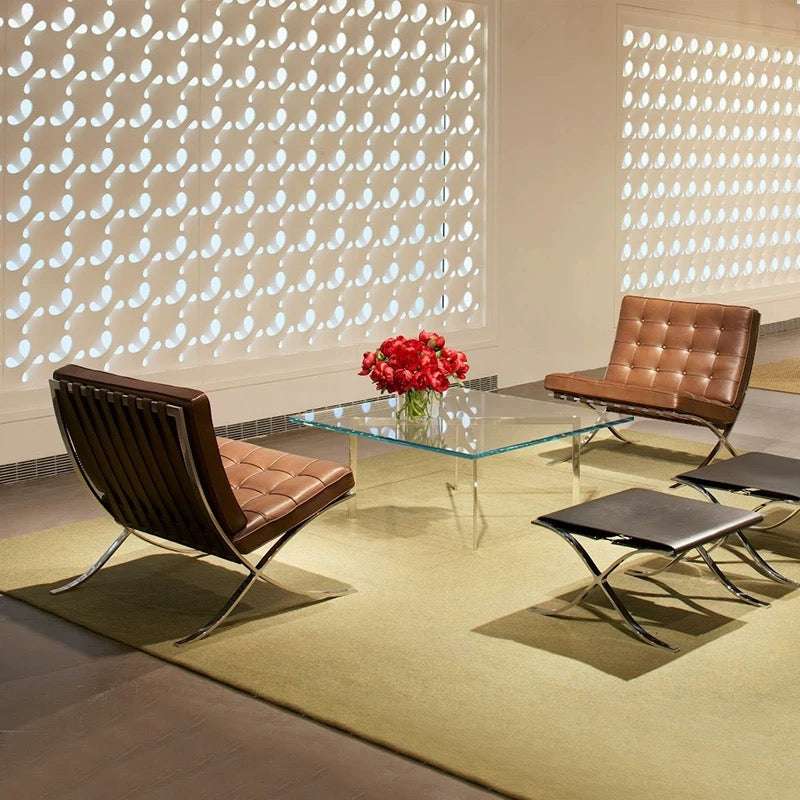 Modern interior with brown leather chairs and a glass coffee table in front of a decorative wall.