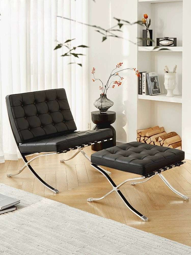 Modern black leather chair and ottoman in a living room setting with a bookshelf and decorative items.