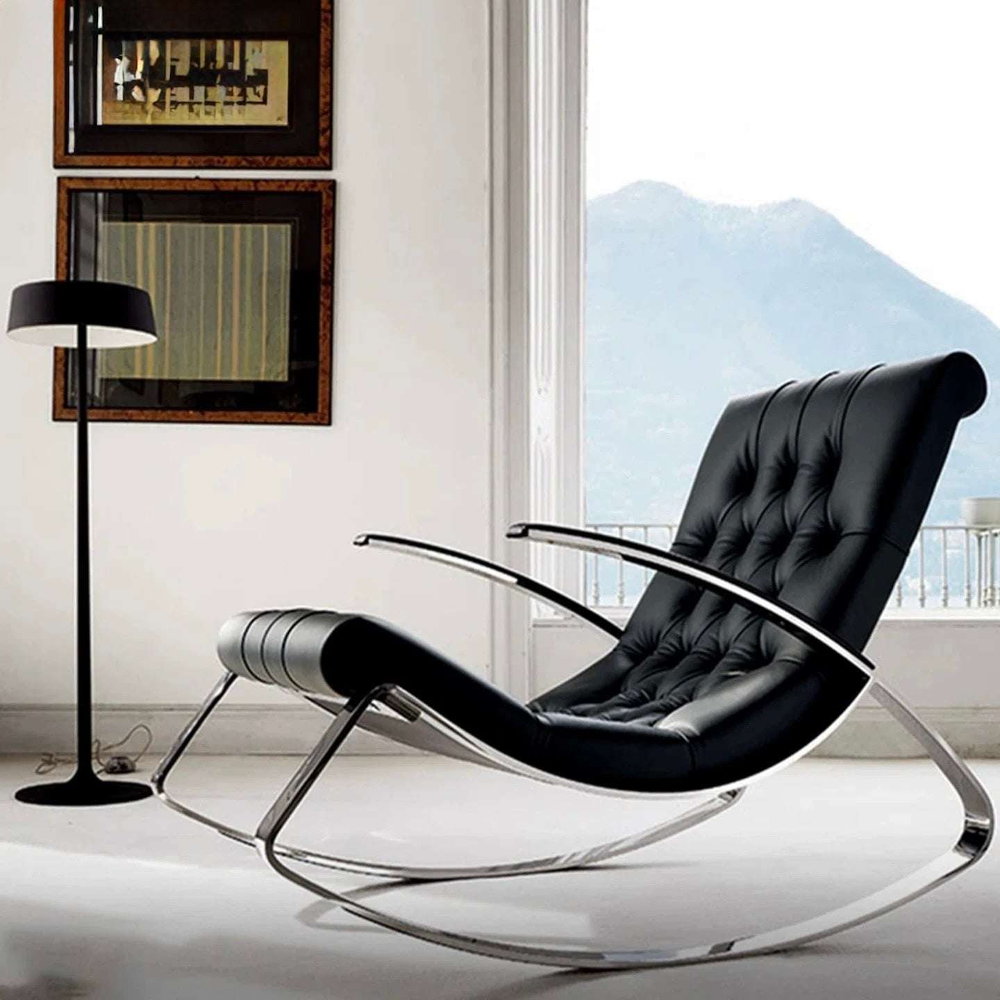 Modern black rocking chair in a stylish room with a lamp and framed pictures.