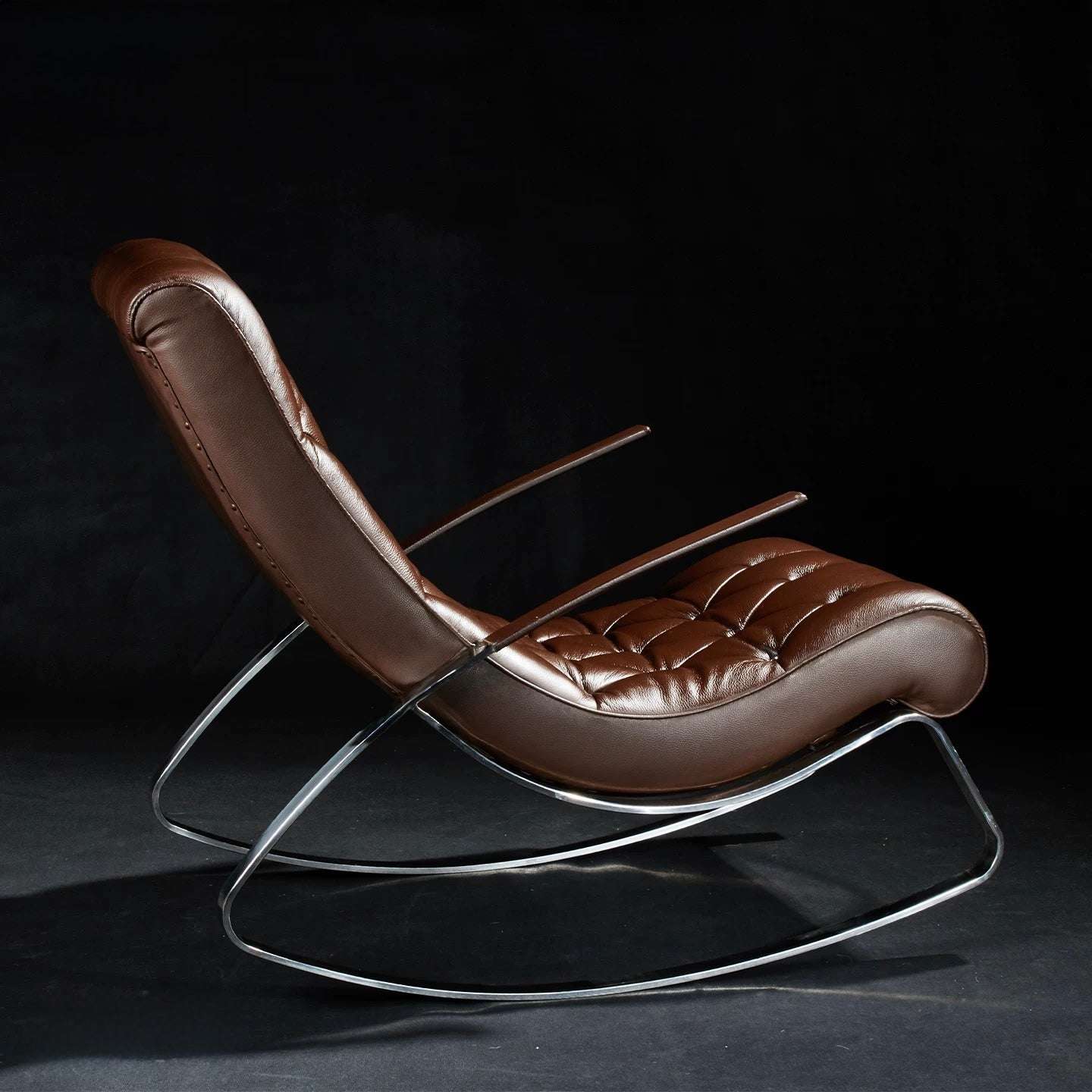 Brown leather lounge chair with metal frame on a dark background
