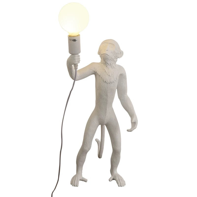 White monkey-shaped lamp holding a light bulb on a white background