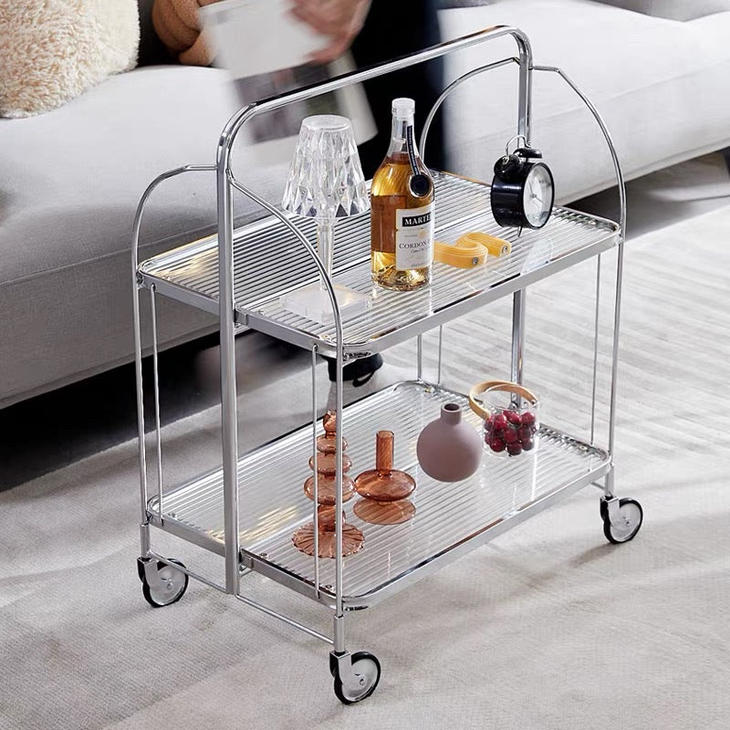 Metal serving cart with drinks and decor items on a light-colored floor.