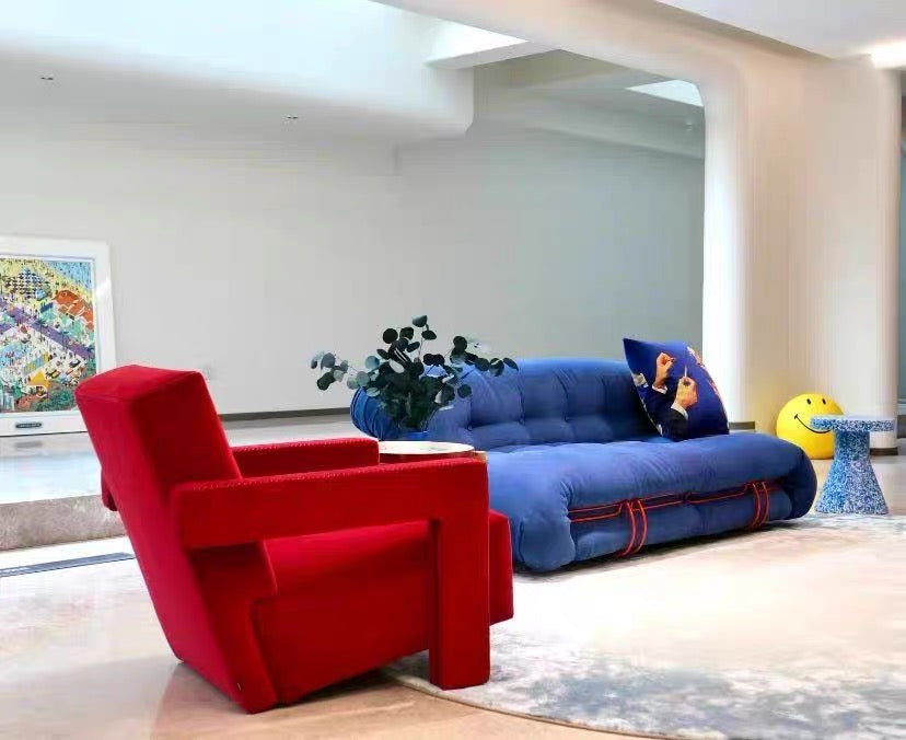 Modern living room with a red armchair and blue sofa.