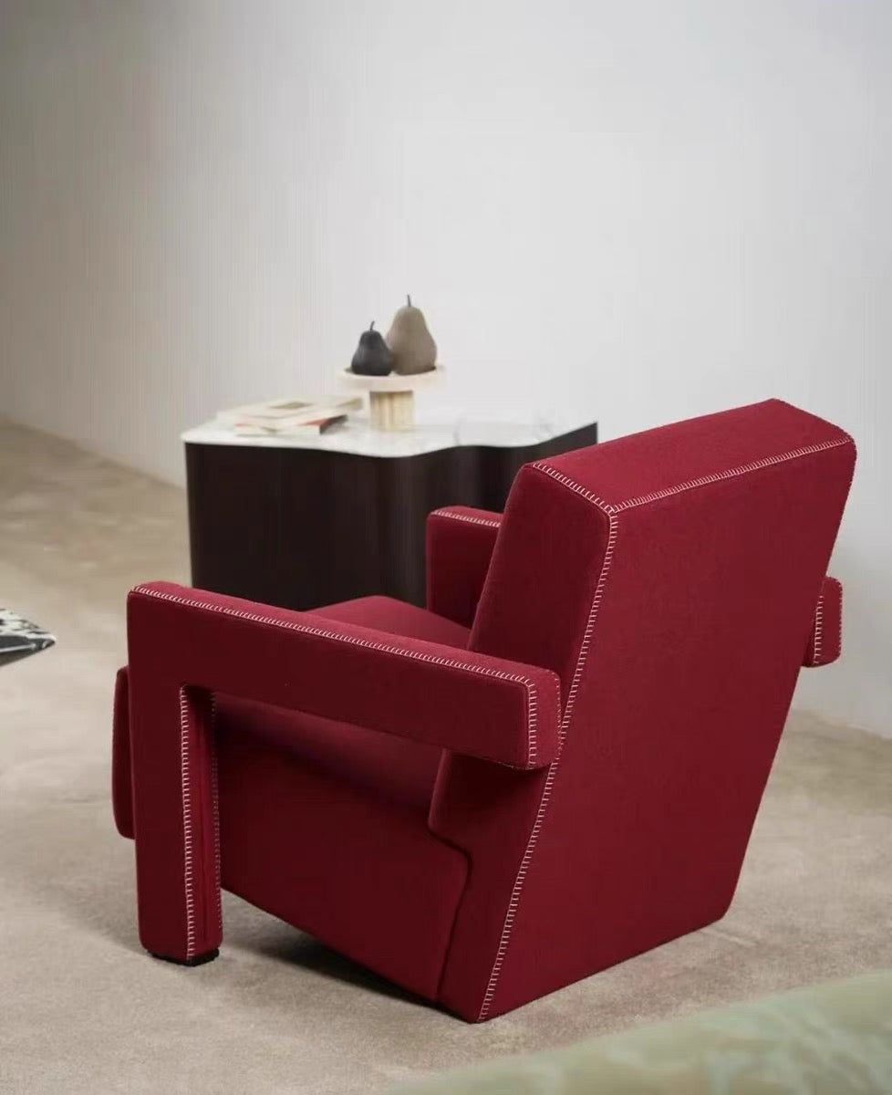 Red armchair in a minimalistic room with a small table and decorative items.