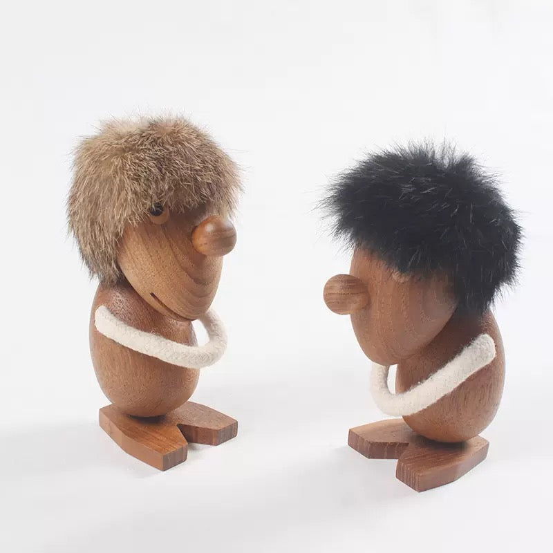 Two wooden figurines with fur and a white band on a white background