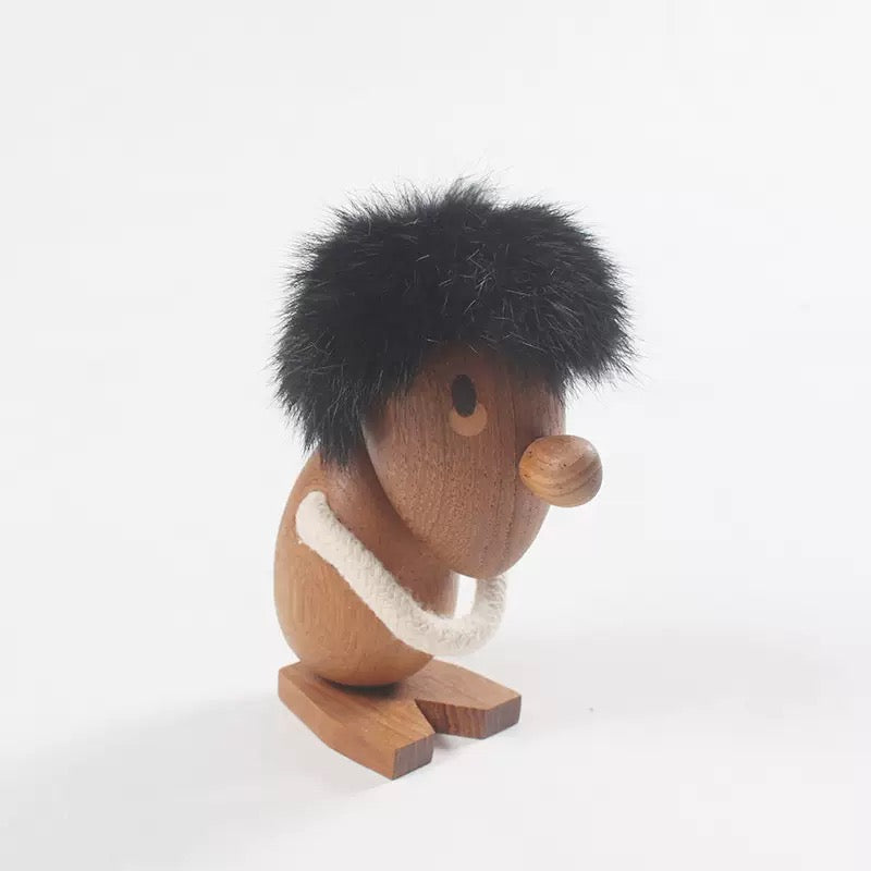 Wooden figurine of a character with black fur, brown body, and white scarf on a white background