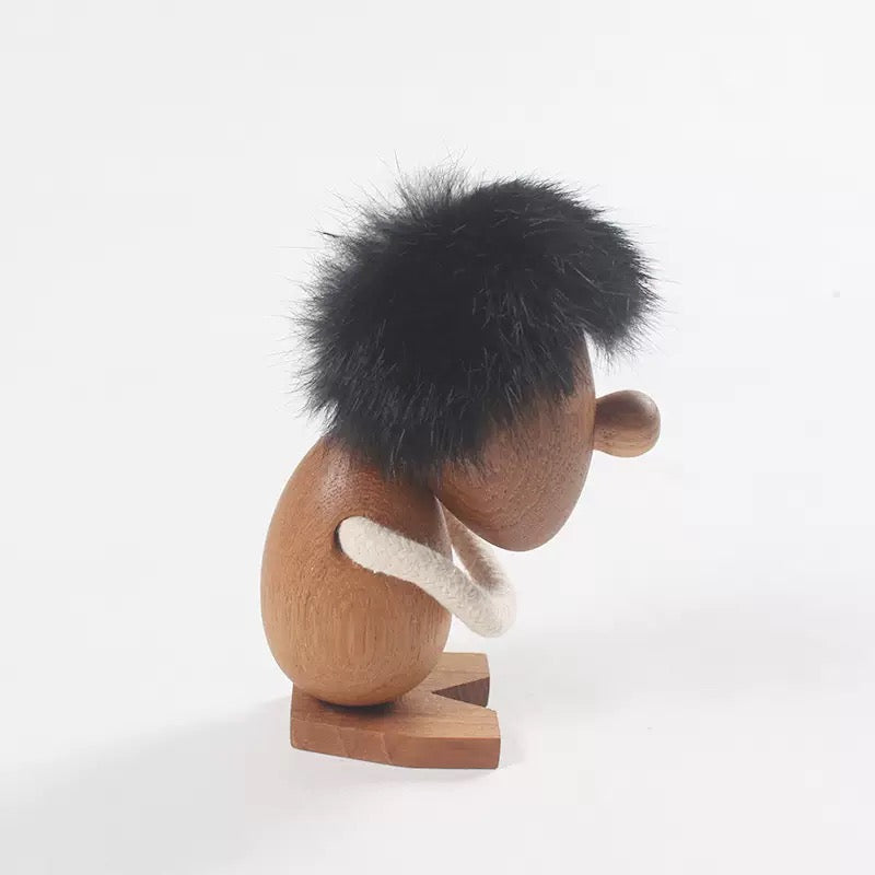 Wooden figurine with black hair and a white scarf on a white background
