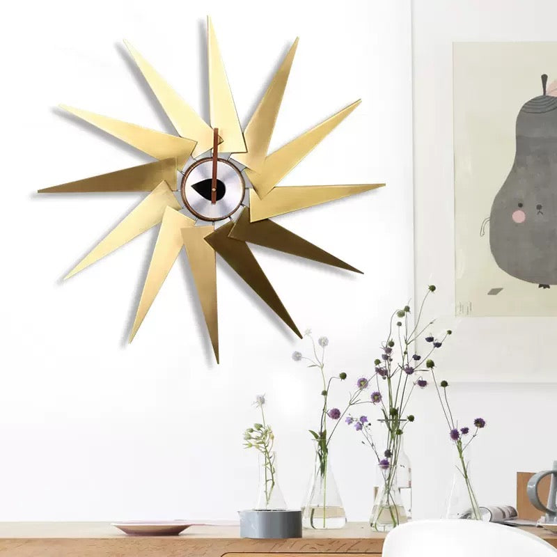 Gold star-shaped wall clock on a white wall with decorative elements.