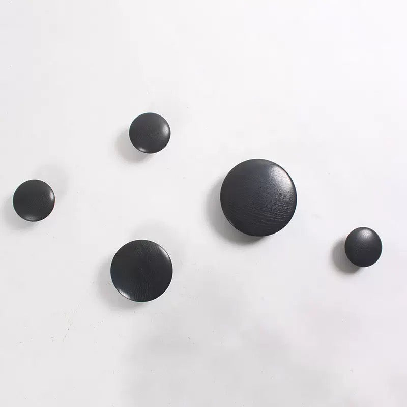 Black round wall hooks on a white background