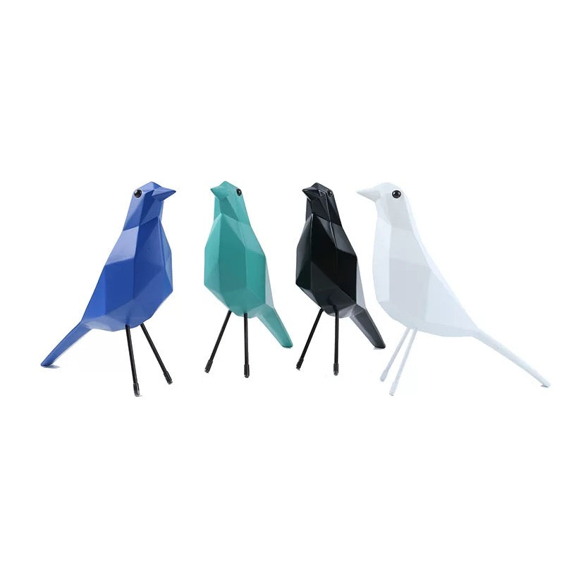 Four geometric bird sculptures in blue, green, black, and white on a white background