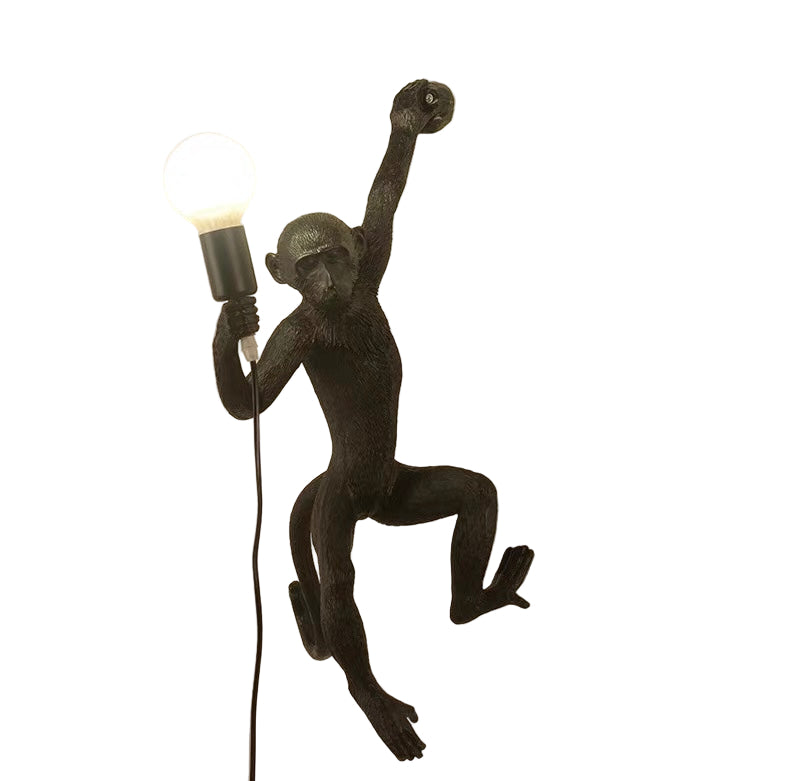 Black monkey-shaped wall light with a bulb on a white background