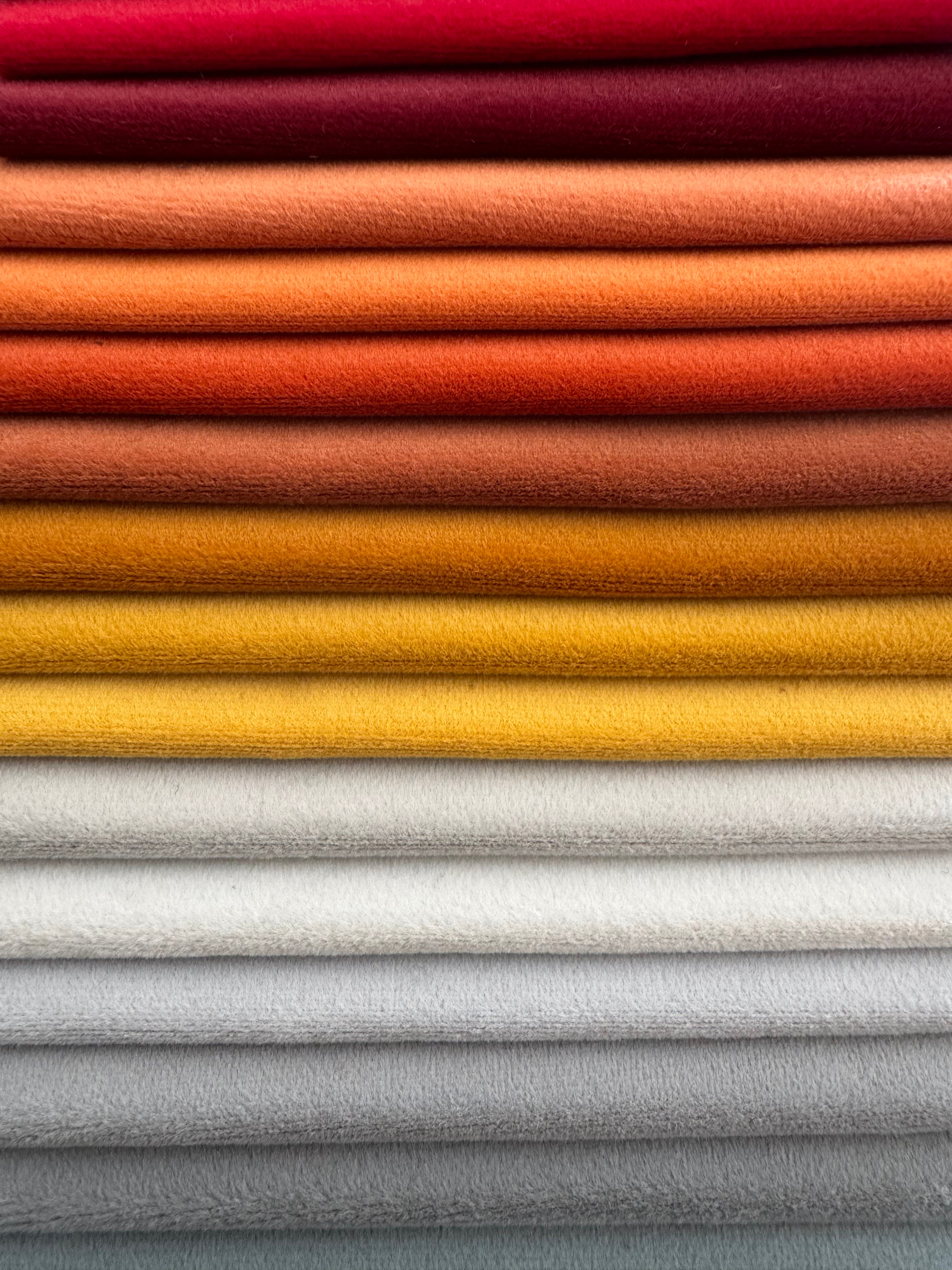 Stack of colorful fabric swatches in red, orange, yellow, and gray.