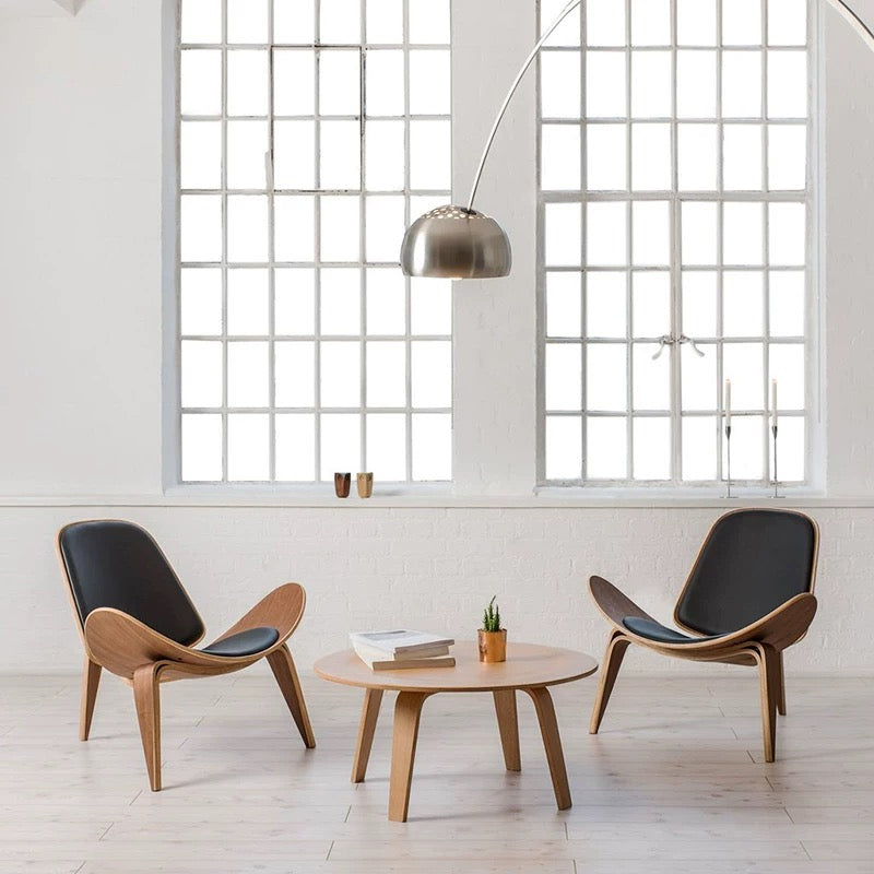 Modern interior with two wooden chairs and a round table in front of large windows.