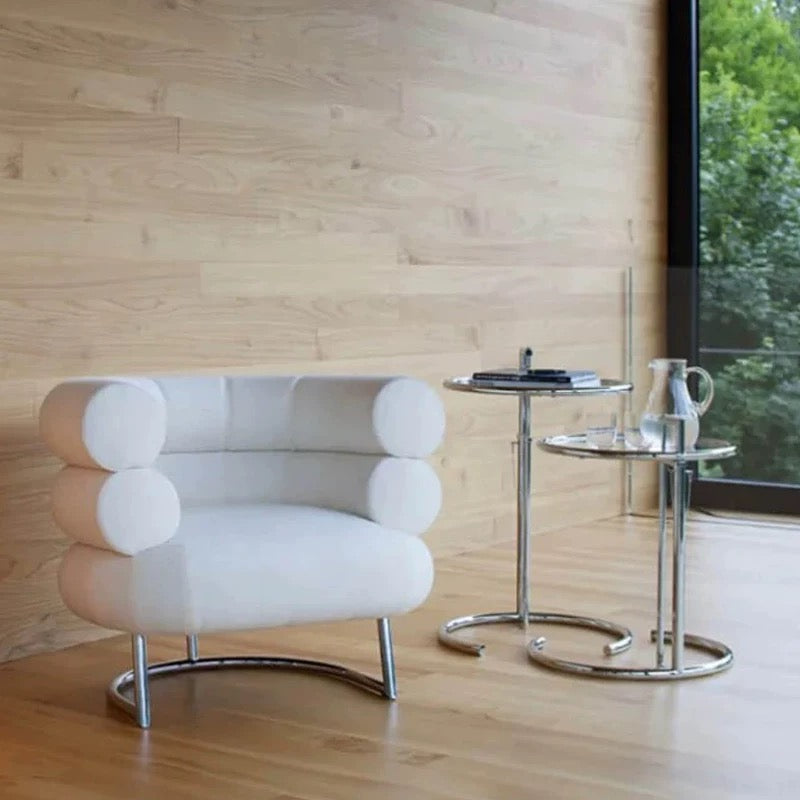 Modern white armchair with chrome legs in a room with wooden walls and a window.