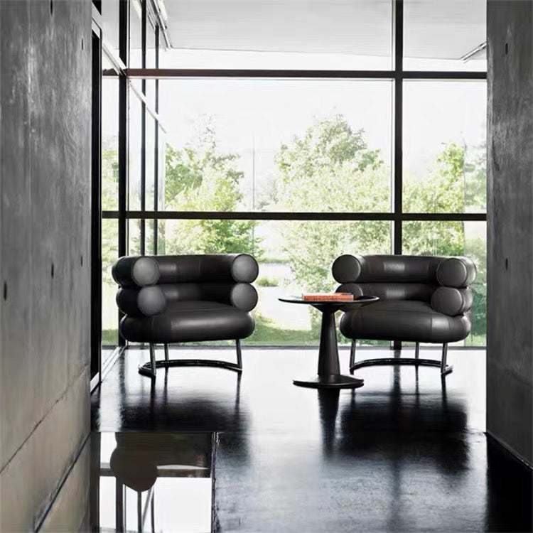 Modern black leather chairs with a table in a room with large windows.