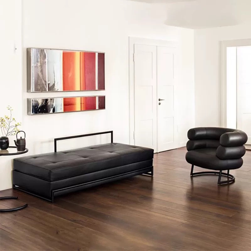 Modern living room with black sofa bed and chair against a white wall.