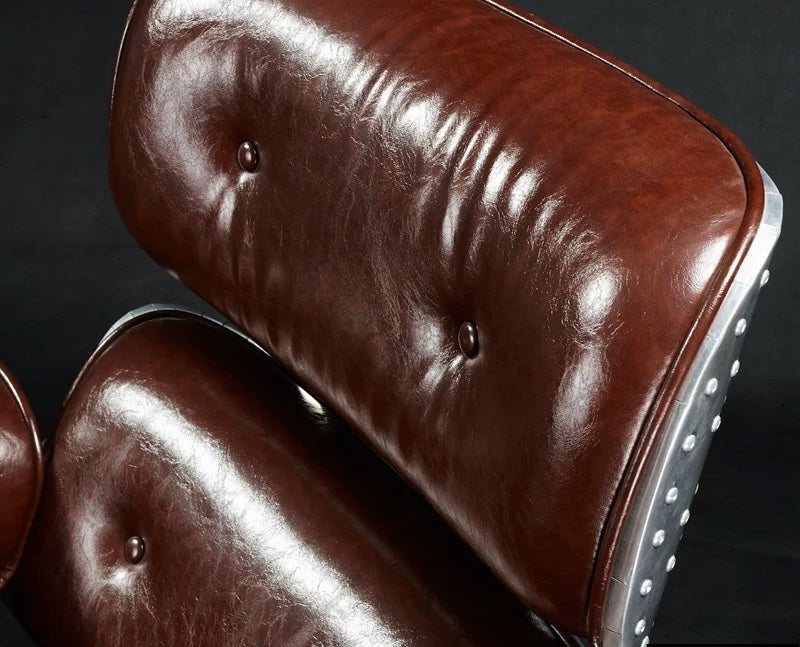 Close-up of a brown leather chair with tufted backrest and studded details.