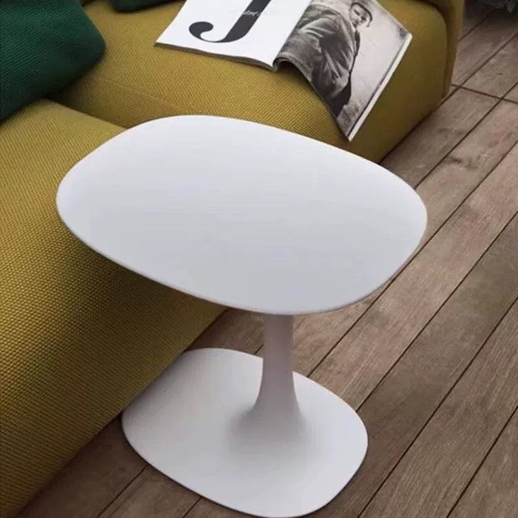 White side table on a wooden floor next to a yellow sofa with a magazine.