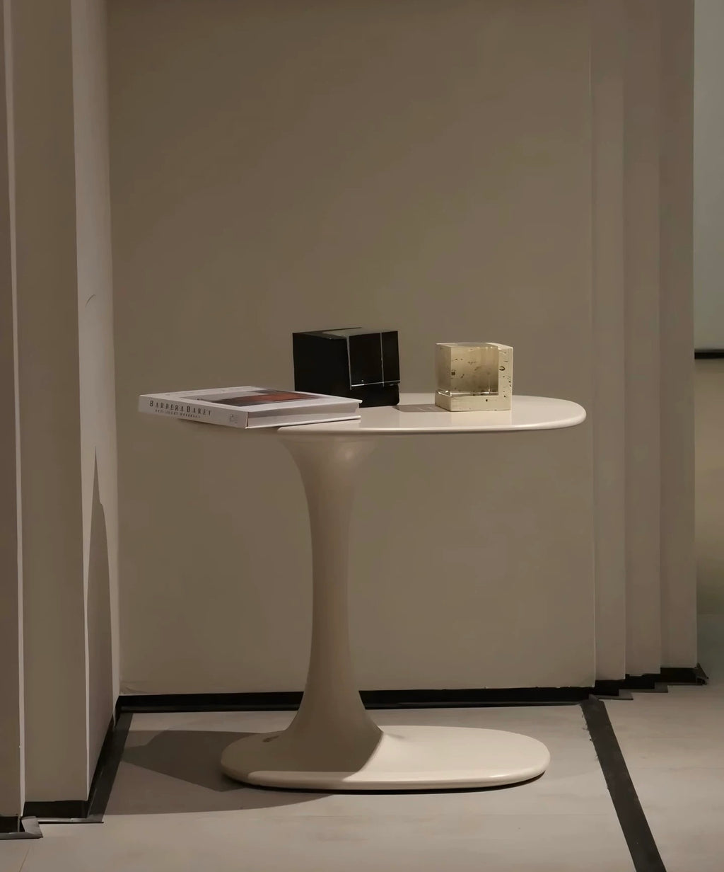Modern white side table with a black cube and a book on a plain wall background