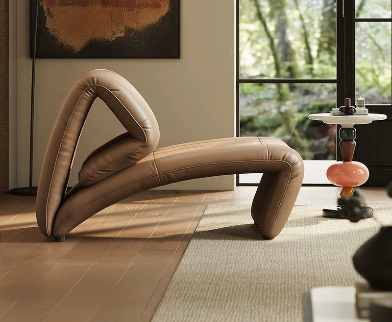 Modern beige lounge chair in a stylish room with a painting and window view.