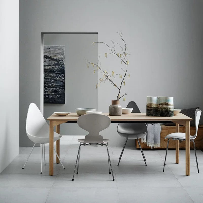 Modern dining room with wooden table and white chairs against a gray wall.