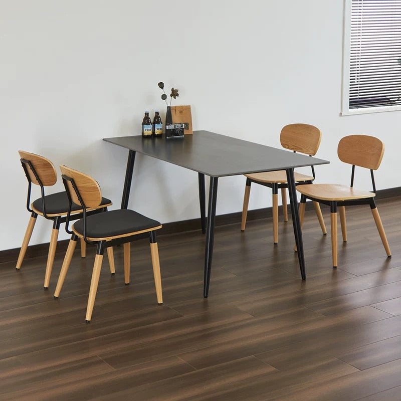 Dining table with four chairs in a room with wooden flooring and a white wall.