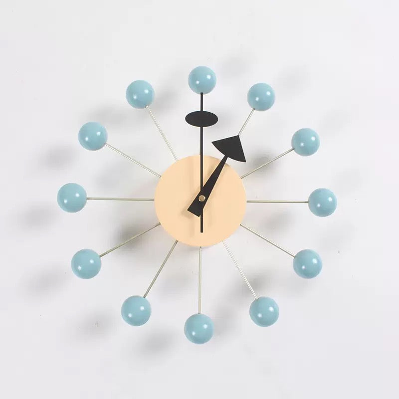 Modern wall clock with light blue spherical accents on a white background