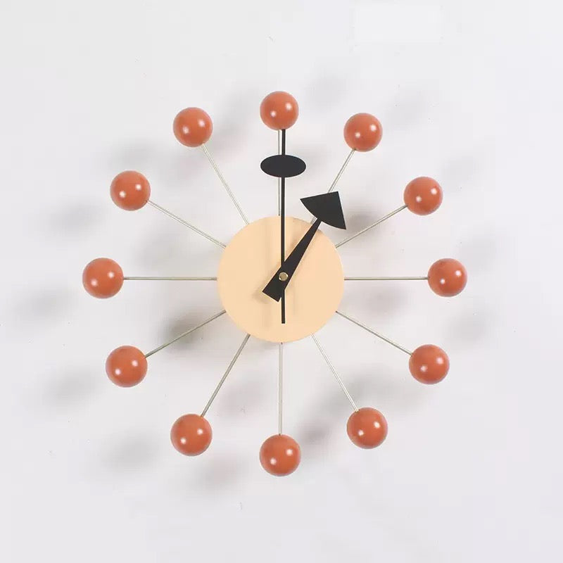 Modern wall clock with orange spherical accents on a white background