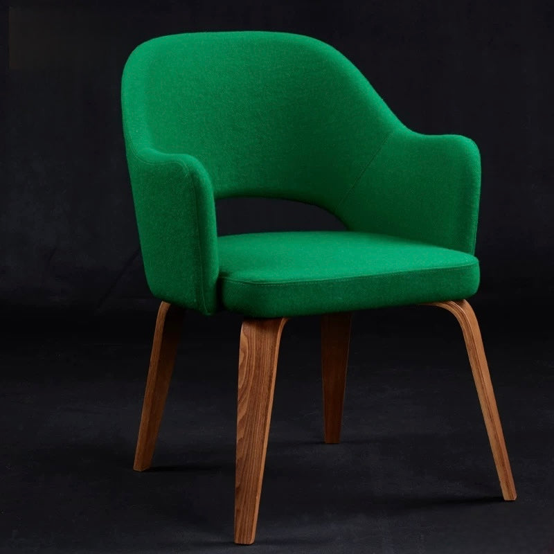 Green upholstered chair with wooden legs on a black background