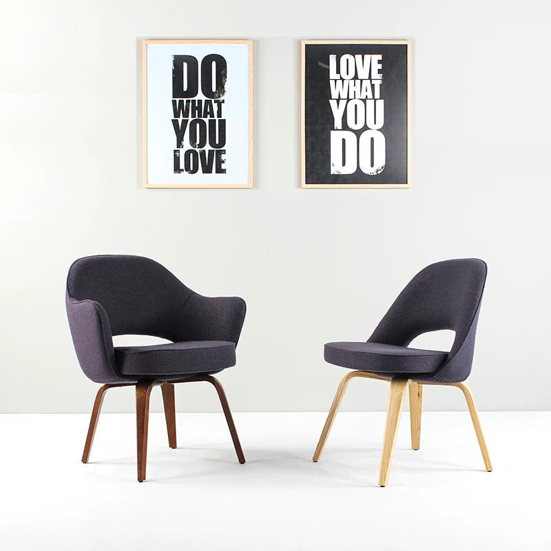 Two dark gray chairs with wooden legs on a white floor, with two motivational posters on the wall.