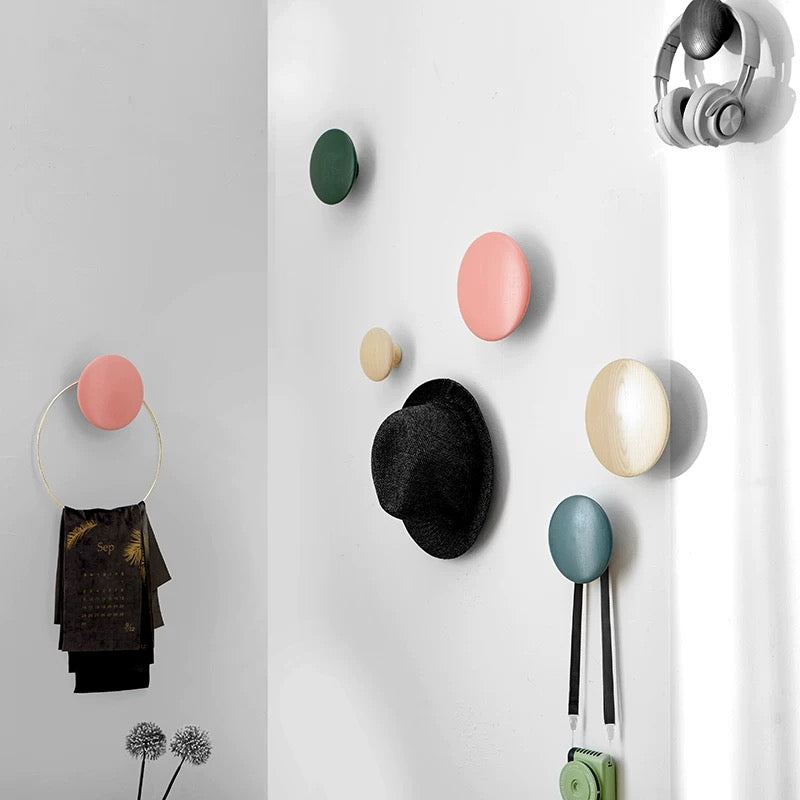Colorful wall hooks on a white wall with various items hanging from them.
