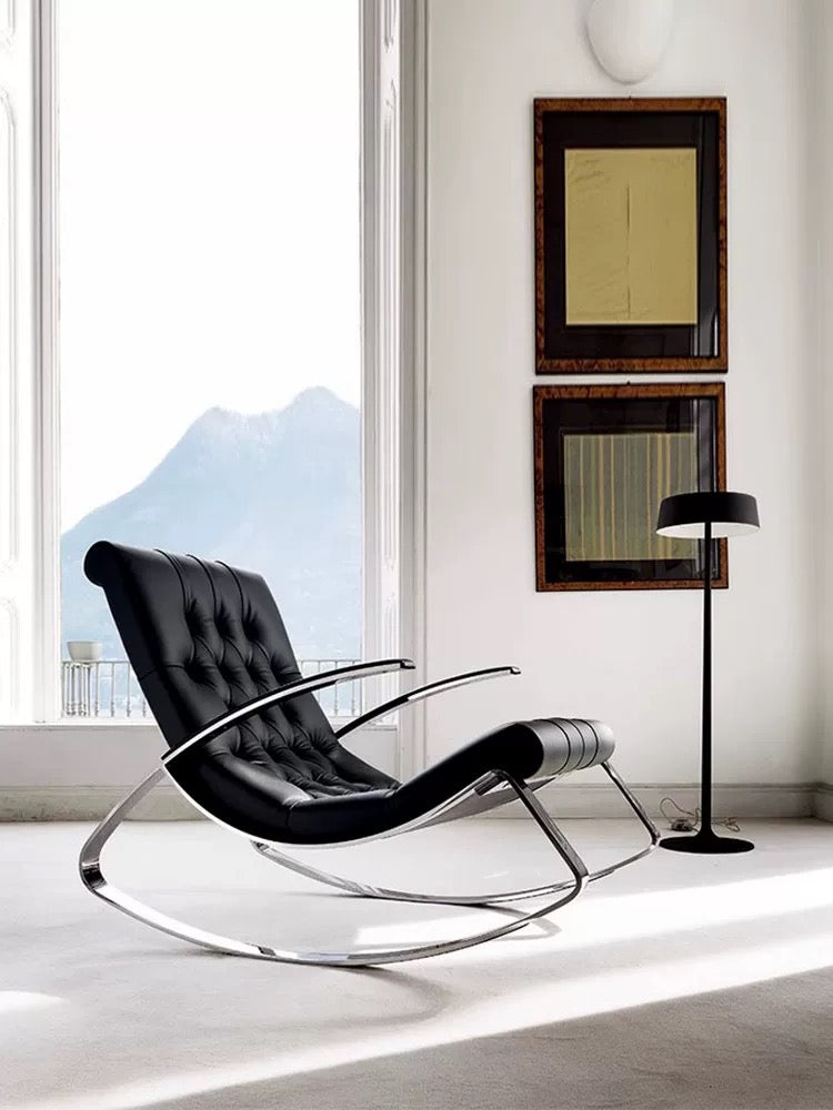 Modern black lounge chair in a room with large windows and framed artwork on the wall.