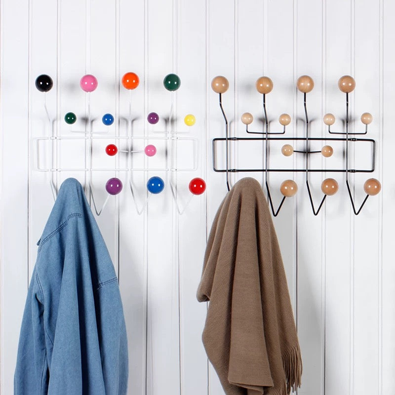 Wall-mounted coat rack with colorful hooks and two hanging coats on a white background