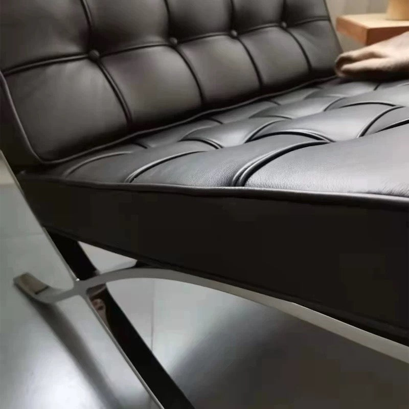 Close-up of a black leather chair with tufted backrest