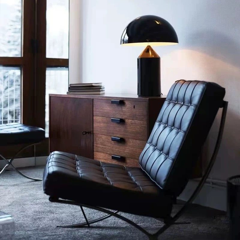 Modern black leather chair in a room with a wooden cabinet and lamp.