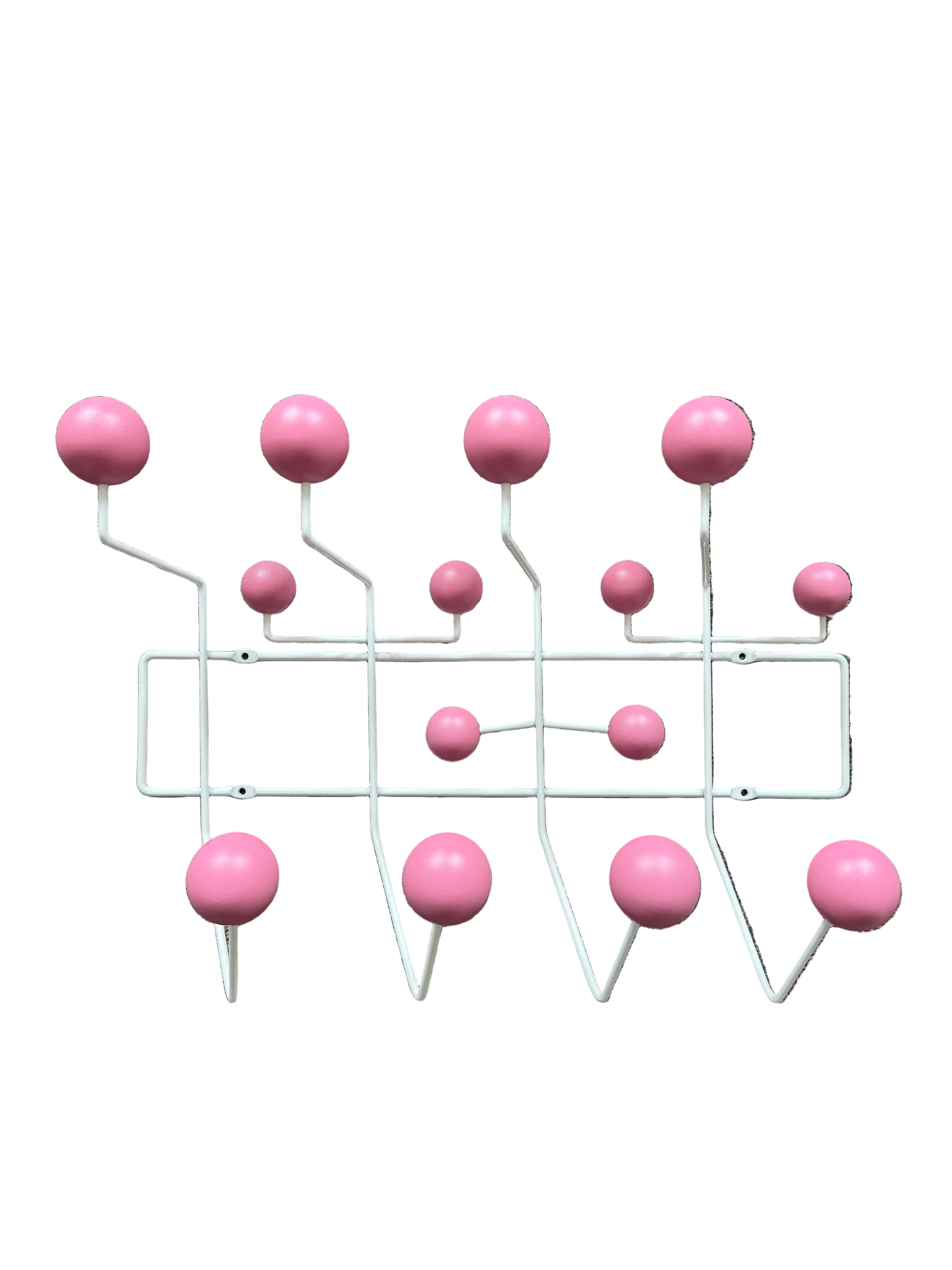 Wall-mounted coat rack with pink balls on a brown textured background