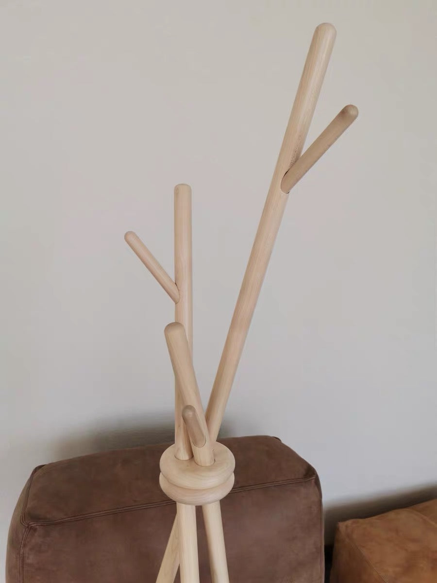 Wooden coat rack with multiple hooks on a brown surface against a plain background