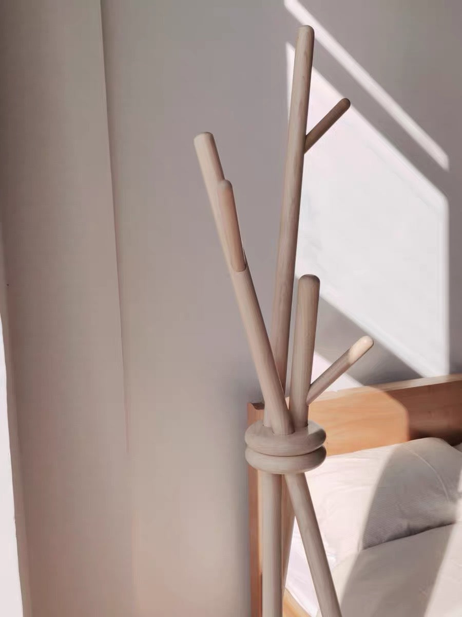 Beige coat rack with multiple hooks against a light-colored wall.