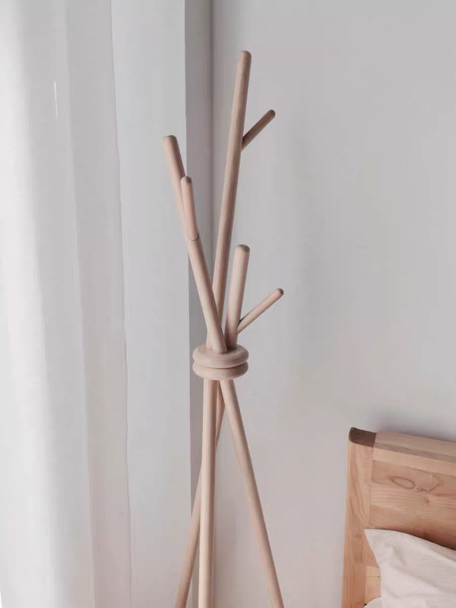 Wooden coat rack with multiple hooks against a white wall.