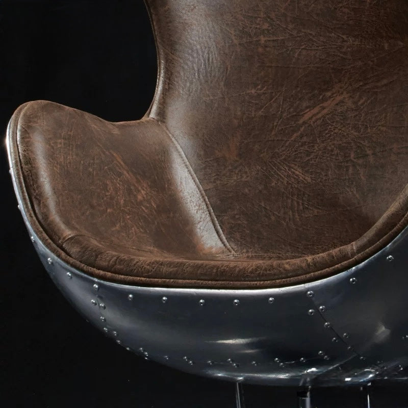 Close-up of a brown leather chair seat with metal rivets on a black background