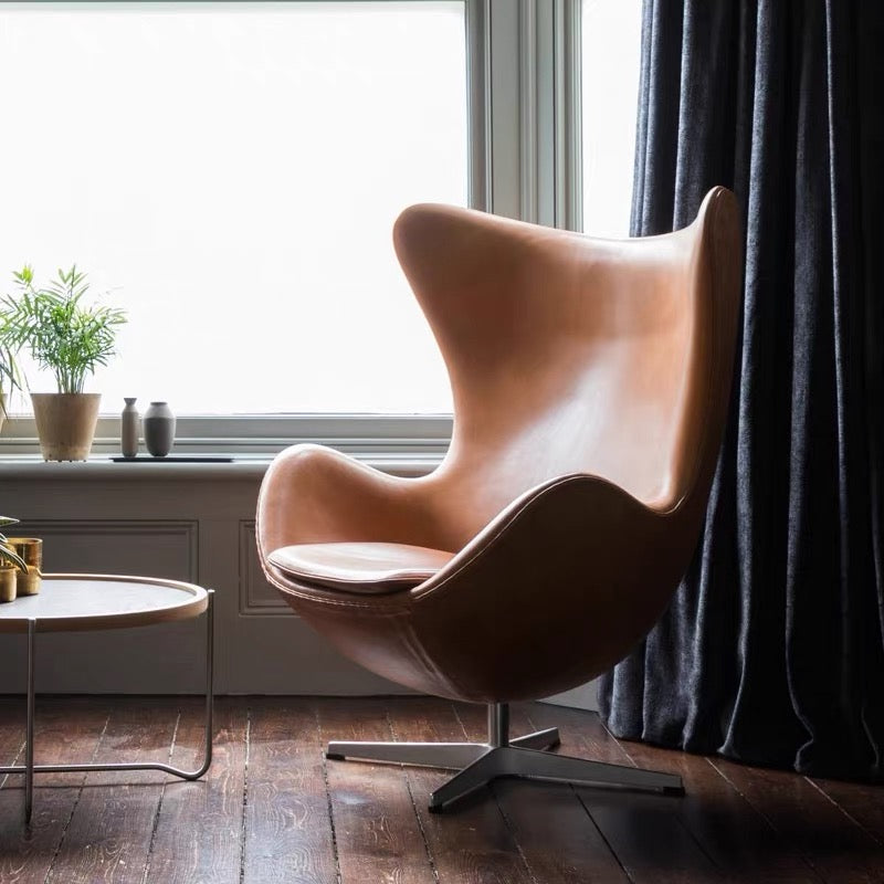 Brown egg-shaped chair in a room with a window and plant