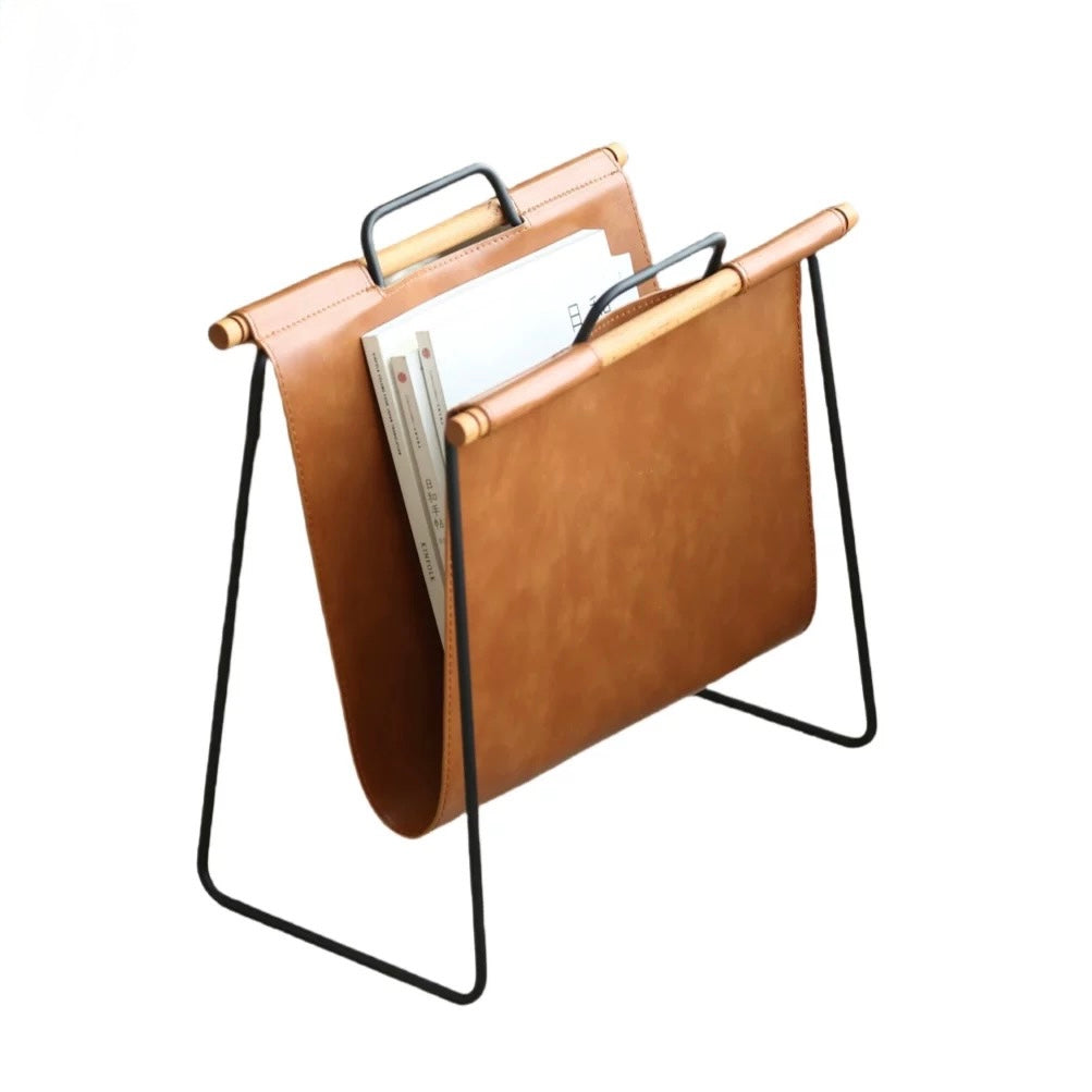 Brown leather magazine rack with black metal legs on a white background