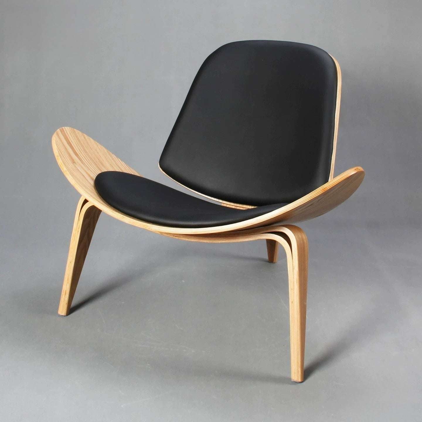 Modern chair with black seat and wooden frame on a gray background