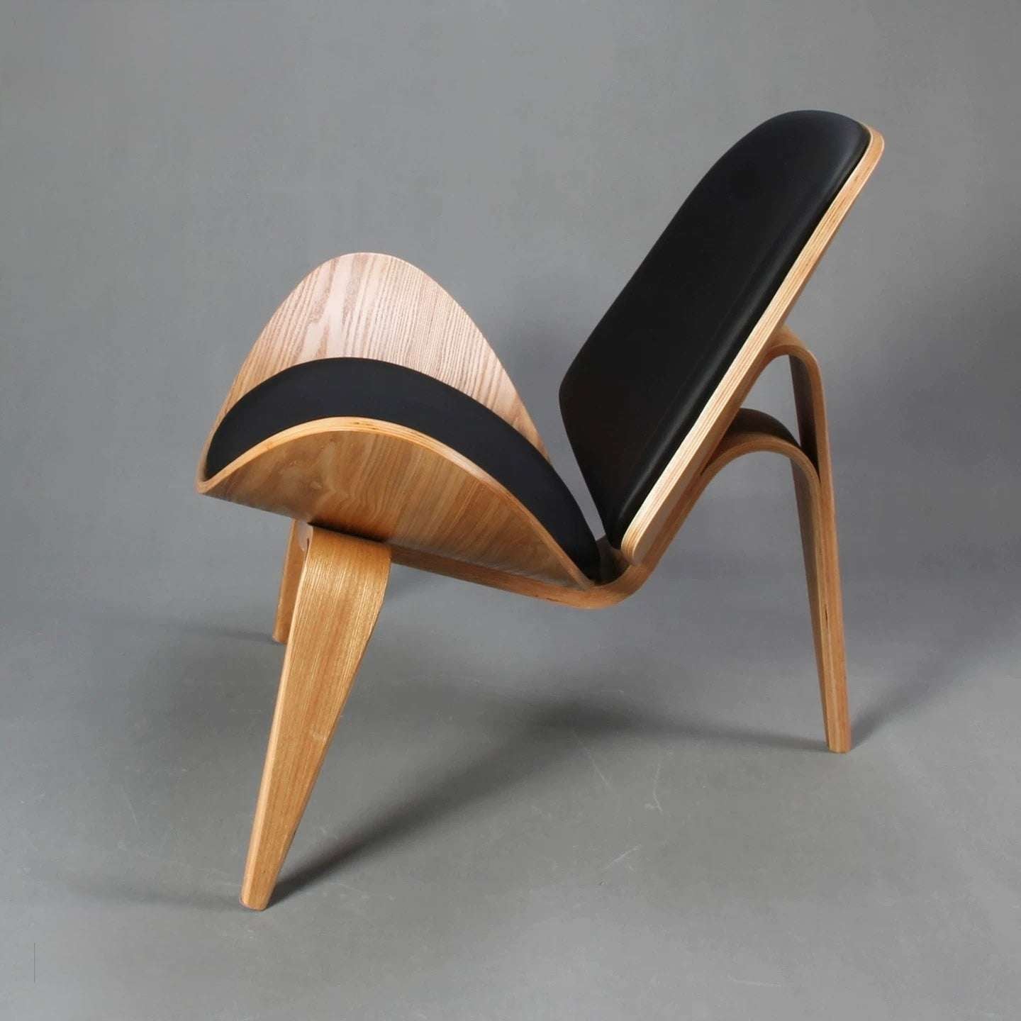 Modern chair with wooden frame and black seat on a gray background